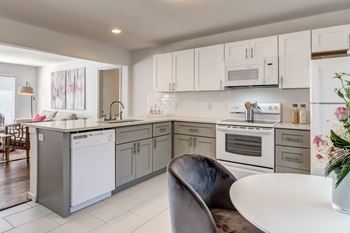 a kitchen with white appliances and a white table and chairs